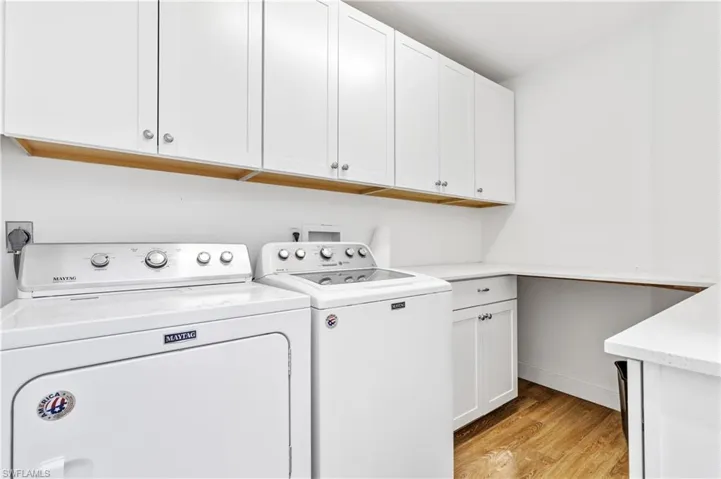 Laundry room featuring light wood-style flooring, separate washer and dryer, and cabinet space