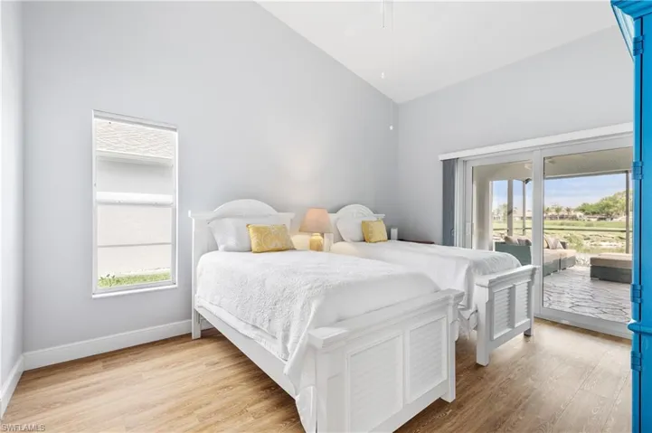 Bedroom featuring light wood-style floors, access to outside, lofted ceiling, and a ceiling fan