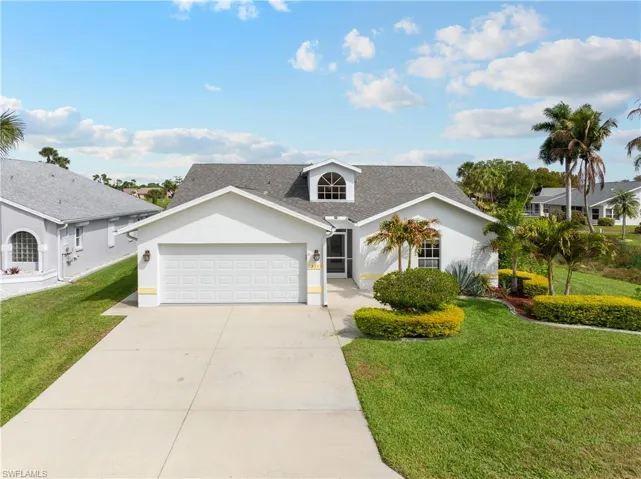 View of front facade featuring stucco siding, a front lawn, driveway, an attached garage, and roof with shingles