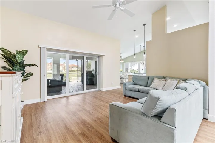 Living room with lofted ceiling, light wood-type flooring, ceiling fan, and recessed lighting