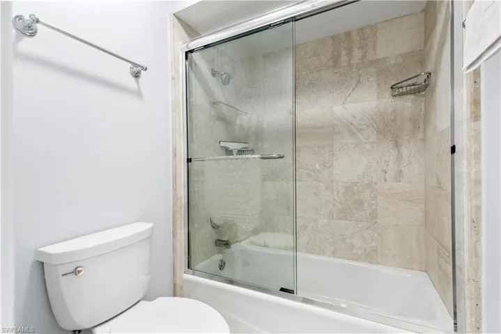 Bathroom with toilet and shower / bath combination with glass door