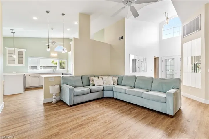 Living area with ceiling fan, light wood finished floors, and vaulted ceiling
