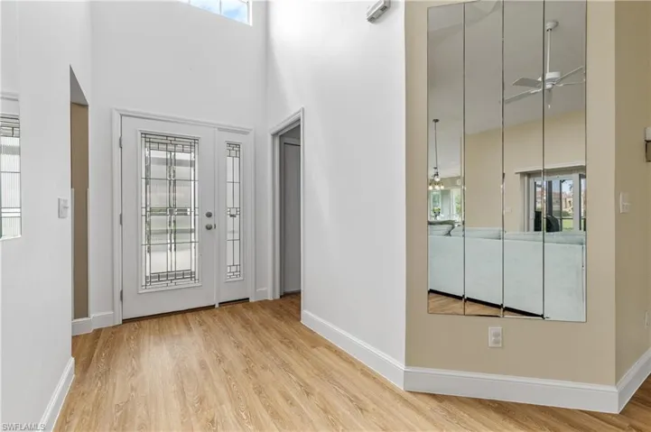 Entrance foyer with a ceiling fan, a high ceiling, and light wood-style flooring