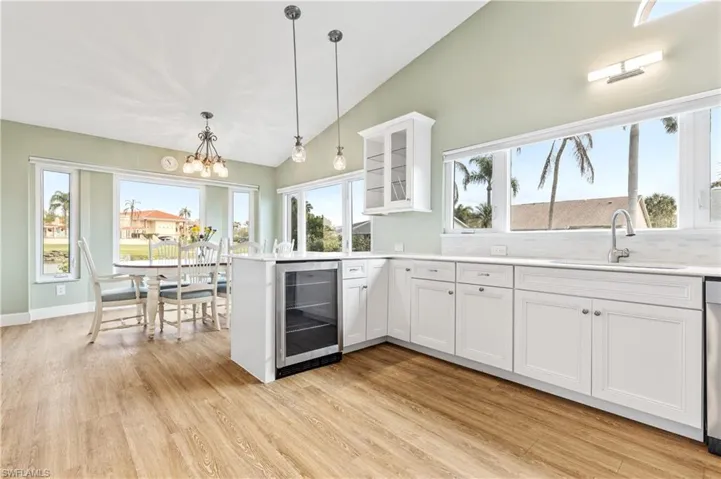 Kitchen with vaulted ceiling, beverage cooler, a peninsula, glass insert cabinets, and white cabinets