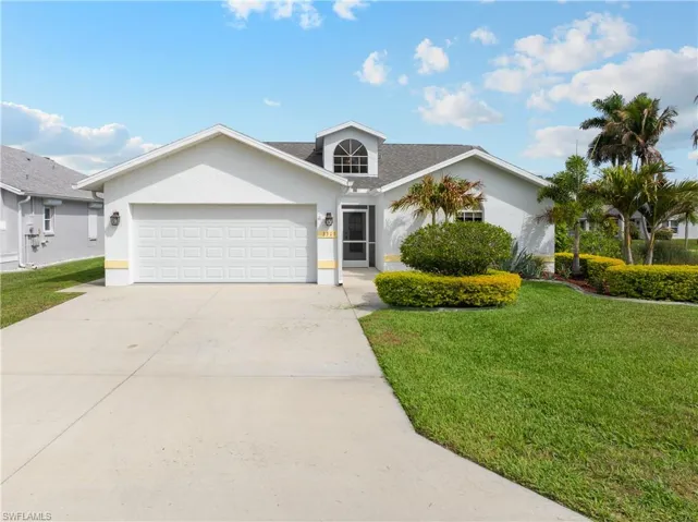 View of front facade with a front lawn, an attached garage, driveway, and stucco siding