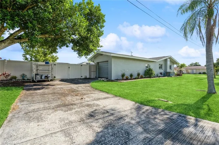 View of side of home with a garage, a lawn, and central AC unit