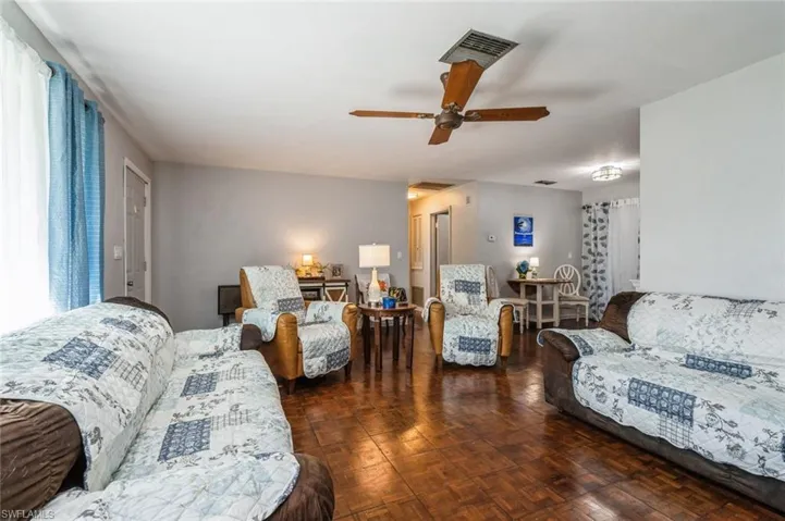 Living room featuring plenty of natural light, dark parquet floors, and ceiling fan