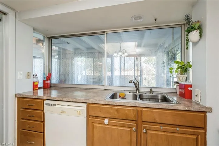 Kitchen with white dishwasher, a notable chandelier, and sink