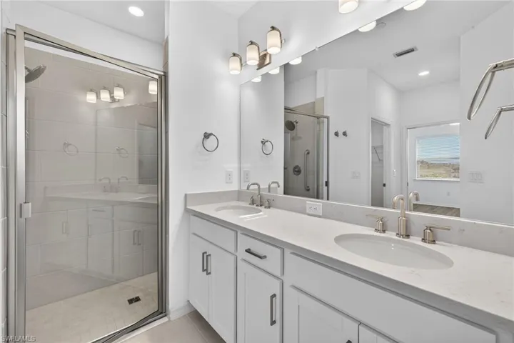 Full bath featuring double vanity, a shower stall, recessed lighting, light tile patterned floors, and a spacious closet