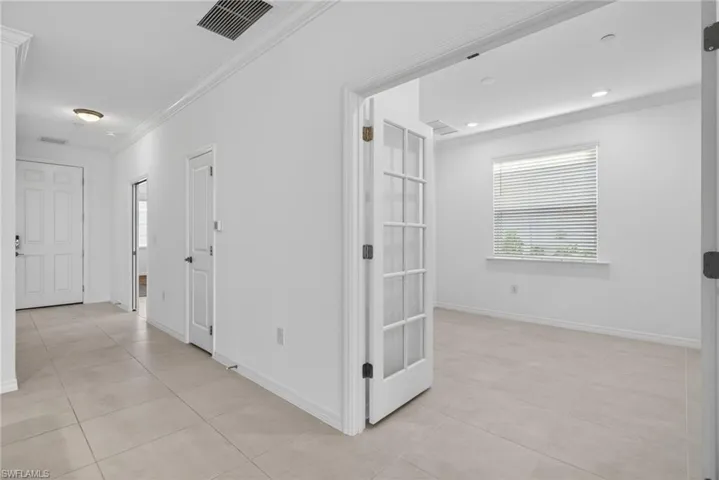 Corridor featuring ornamental molding and light tile patterned flooring