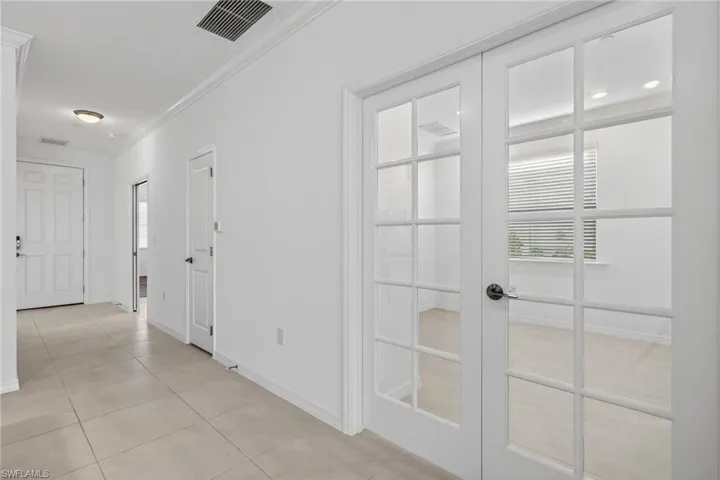 Hall with french doors, ornamental molding, and light tile patterned flooring