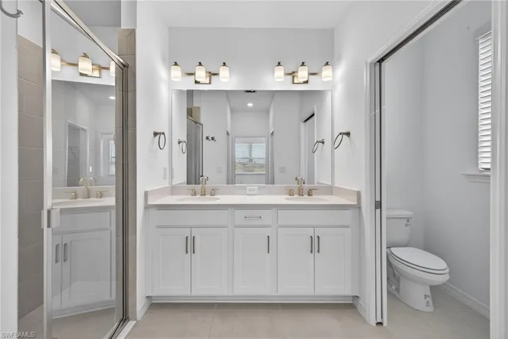 Bathroom featuring double vanity, a stall shower, and light tile patterned flooring