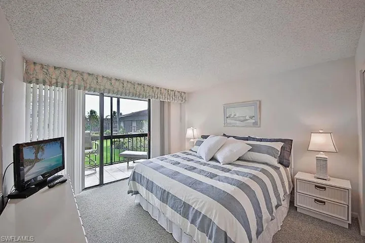 Carpeted bedroom with a textured ceiling and access to exterior