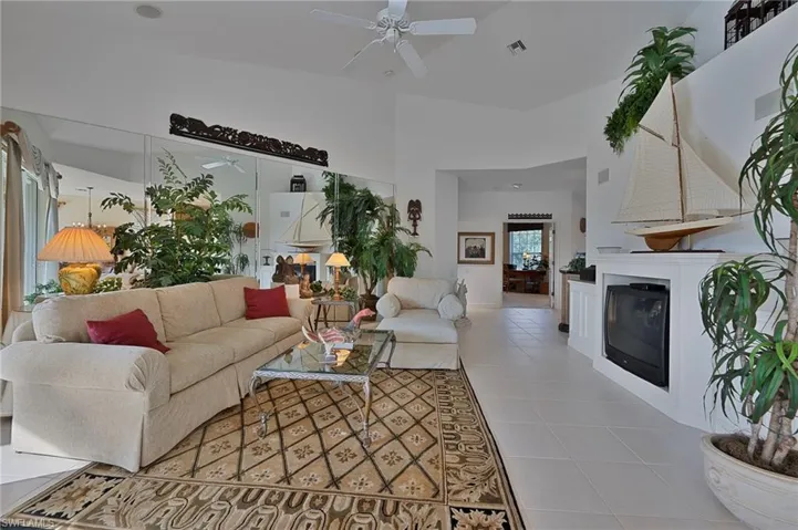 Tiled living room with ceiling fan and high vaulted ceiling