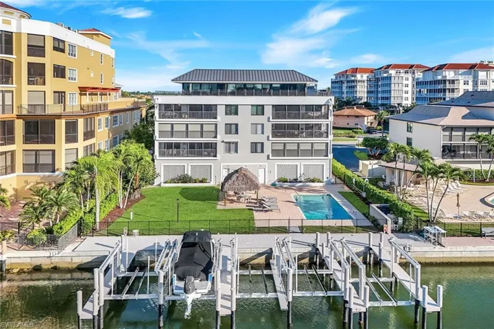 Dock area featuring boat lift, a fenced backyard, a water view, and a community pool