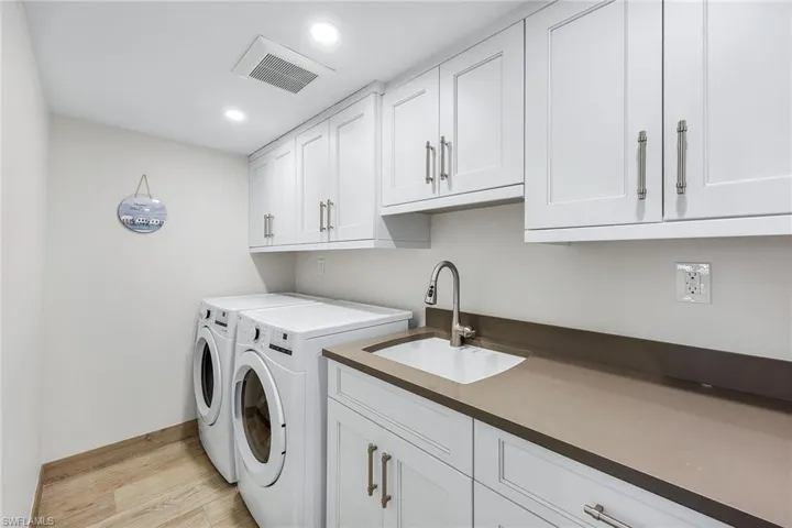 Washroom with washing machine and clothes dryer, light wood-type flooring, cabinet space, and recessed lighting