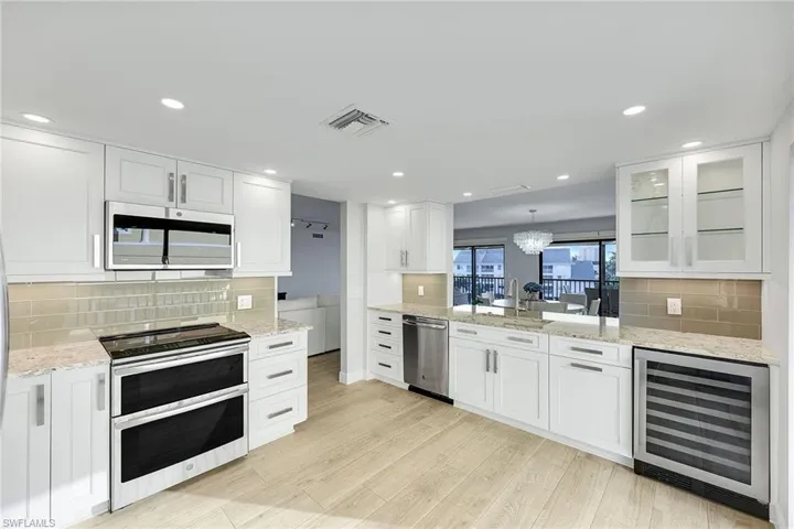 Kitchen featuring stainless steel appliances, backsplash, wine cooler, white cabinets, and recessed lighting