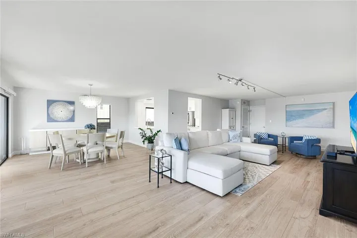 Living area featuring light wood-style floors, a chandelier, and track lighting