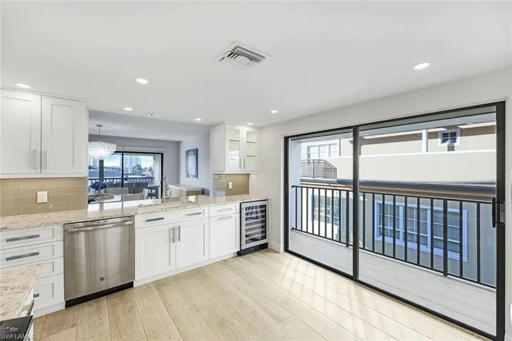 Kitchen featuring tasteful backsplash, dishwasher, light stone countertops, white cabinetry, and recessed lighting