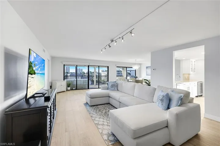 Living area with track lighting, light wood finished floors, a chandelier, and beverage cooler