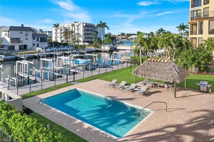 Community pool with a water view, a patio, boat lift, and a boat dock
