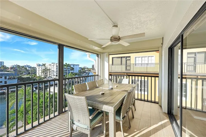Sunroom featuring a balcony, a water view, outdoor dining space, ceiling fan, and a textured ceiling