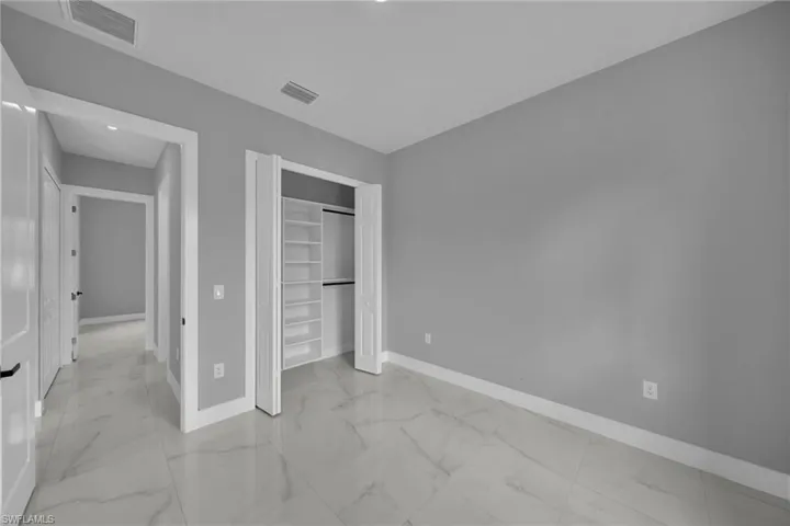 Unfurnished bedroom with light marble finish floors and a closet