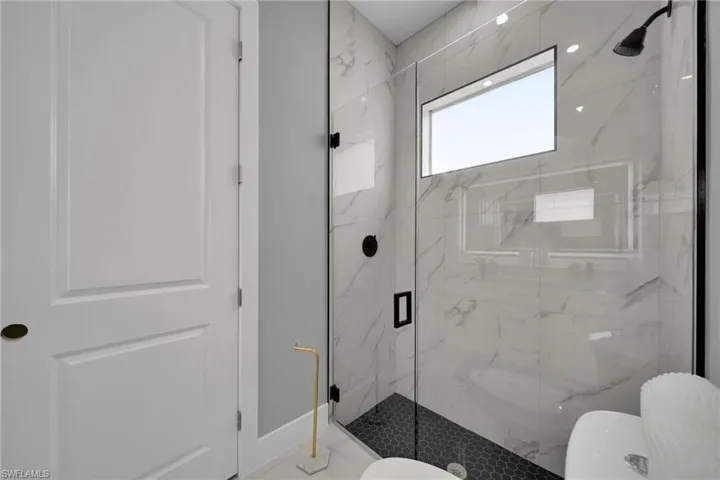 Full bathroom with toilet and a marble finish shower