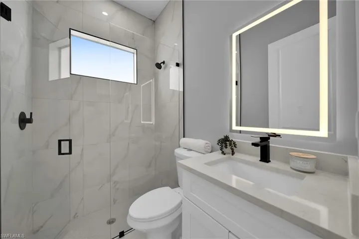 Bathroom featuring a marble finish shower and vanity