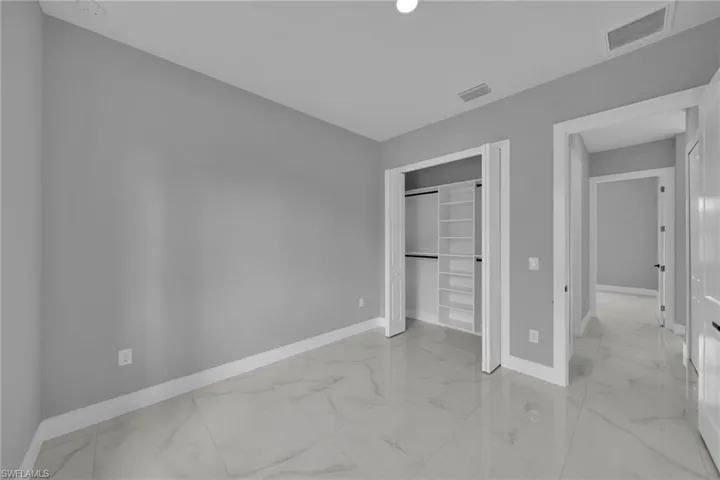 Unfurnished bedroom with light marble finish flooring and a closet