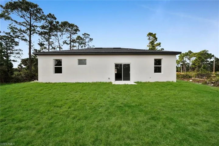 Back of house with a yard and stucco siding
