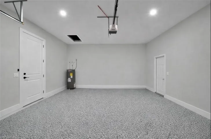 Garage featuring water heater, a garage door opener, and recessed lighting