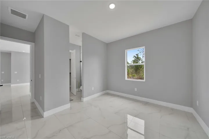 Empty room with light marble finish floors and recessed lighting