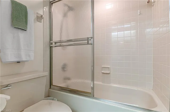 Guest bathroom with toilet and enclosed tub / shower combo
