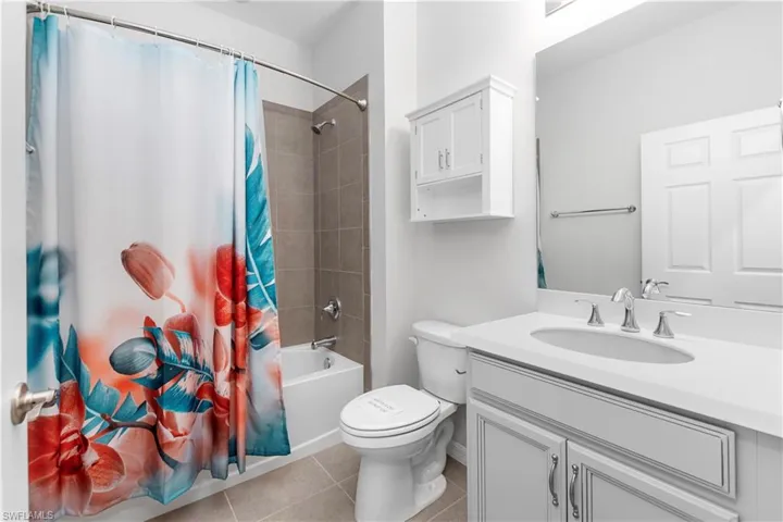 Full bathroom with vanity, tile flooring, toilet, and shower/tub combo