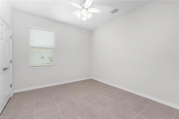 Tiled spare bedroom featuring ceiling fan