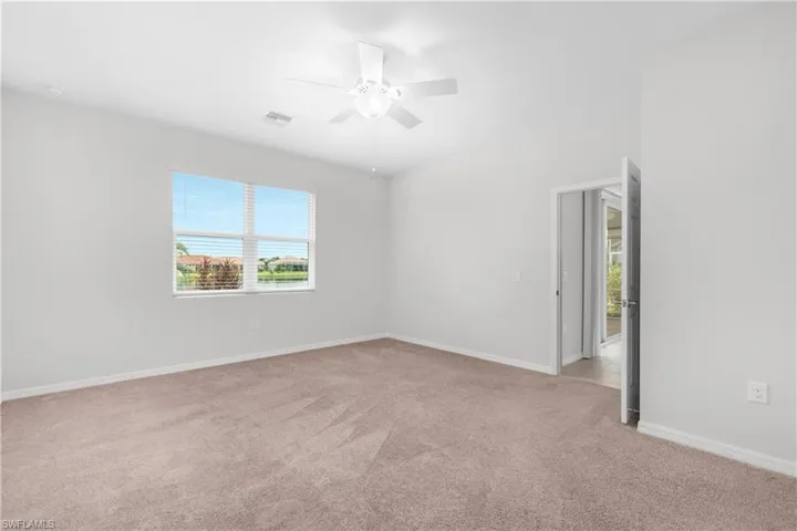 Carpeted master bedroom featuring ceiling fan