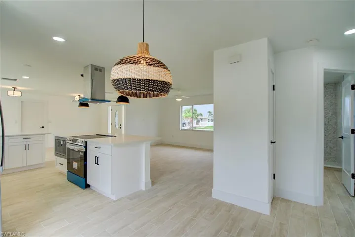 Kitchen featuring appliances with stainless steel finishes, island range hood, open floor plan, baseboards, and recessed lighting