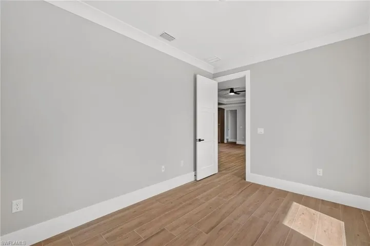 Wood-finish tile flooring, crown molding, crisp white trim, and a contemporary panel door with matte black hardware