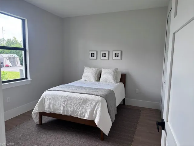 Neutral-toned interior featuring wood-finish flooring, a large single-hung window with a dark frame, and a white paneled closet door with matte black hardware