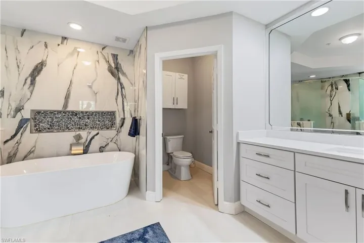 Bathroom with tile flooring, tile walls, toilet, and vanity
