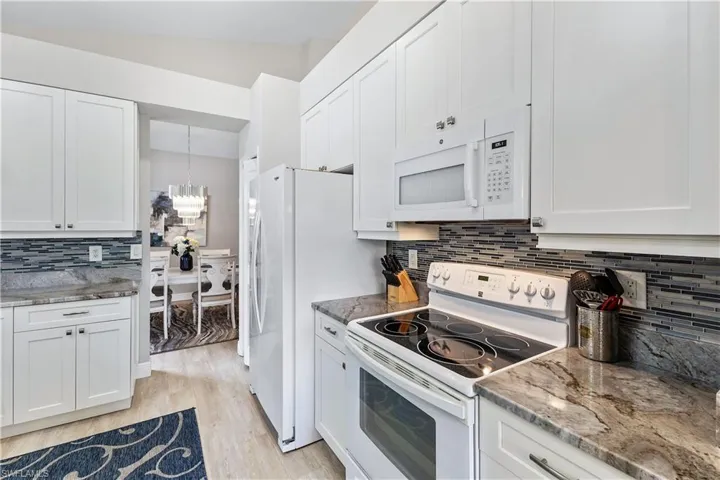 Kitchen with light hardwood / wood-style floors, white appliances, and white cabinetry