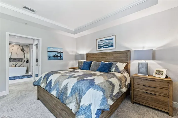 Bedroom featuring light carpet, ornamental molding, and a tray ceiling