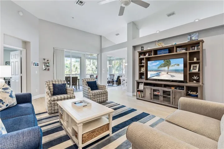 Living room featuring high vaulted ceiling, ceiling fan, and light hardwood / wood-style floors