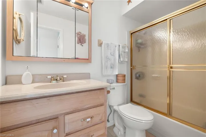 Full bathroom with toilet, vanity, shower / bath combination with glass door, and tile patterned flooring