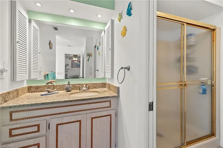 Bathroom with vanity, a shower with shower door, and ceiling fan