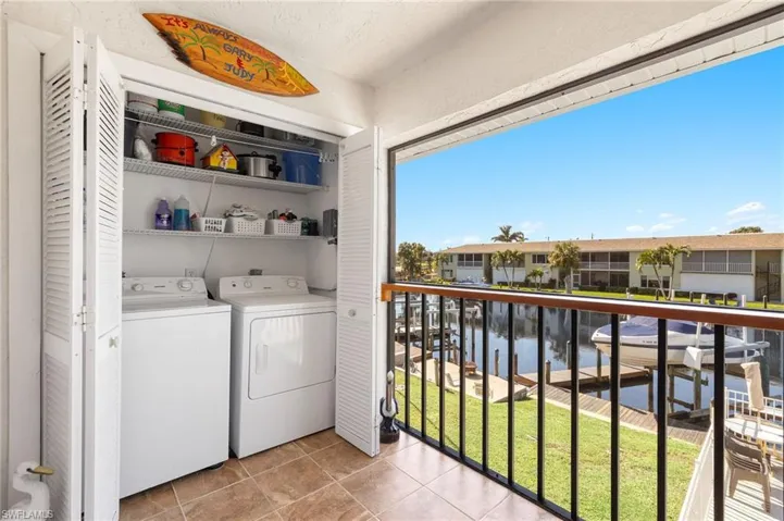 Washroom featuring light tile patterned flooring, a water view, and washing machine and clothes dryer