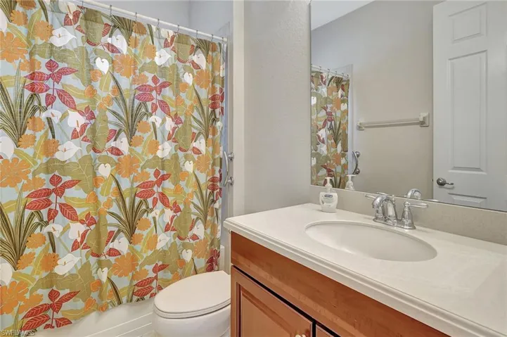 Full bathroom for guests and door leading out to lanai, pool.