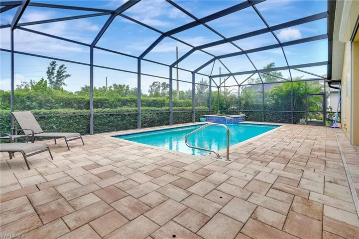 View of swimming pool/spa with spillover water feature in a screen enclosure