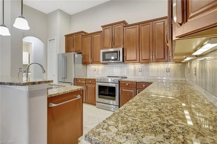 Kitchen featuring light tile patterned flooring, pendant lighting, stainless steel appliances, and tasteful backsplash